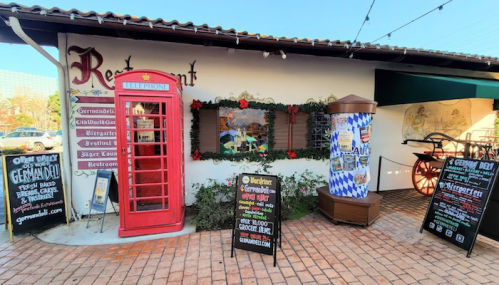 A charming restaurant exterior featuring a red phone booth, festive decorations, and menu boards.