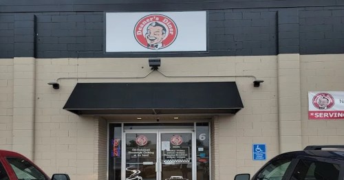 Exterior of a diner with a sign featuring a smiling chef logo, black awning, and large glass entrance.