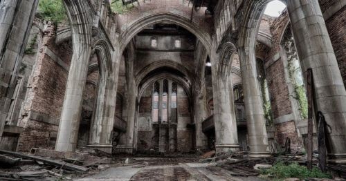 A dilapidated interior of a ruined church, featuring tall arches, crumbling walls, and overgrown vegetation.