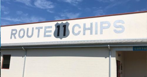 Sign on a building displaying "Route 11 Chips" against a blue sky.