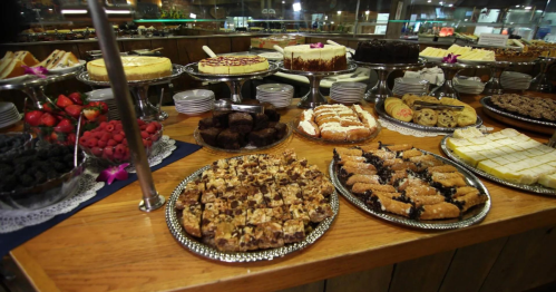 A variety of desserts displayed on a wooden table, including cakes, pastries, and fresh berries.