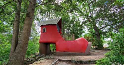 A large red shoe-shaped structure surrounded by trees, resembling a whimsical playhouse or attraction.