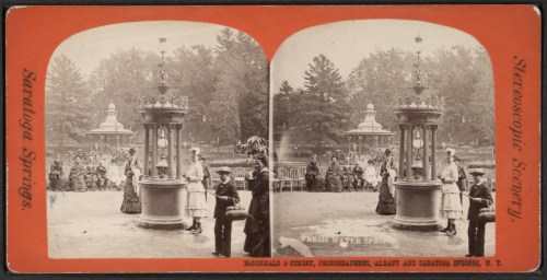 A vintage photo of a water fountain surrounded by people in period clothing at Saratoga Springs.