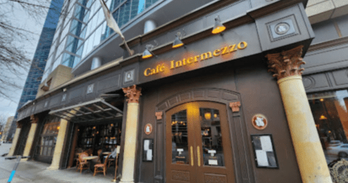 Exterior view of Café Intermezzo, featuring a stylish entrance with columns and large windows in an urban setting.