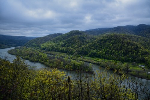 A scenic view of a river winding through lush green hills under a cloudy sky.