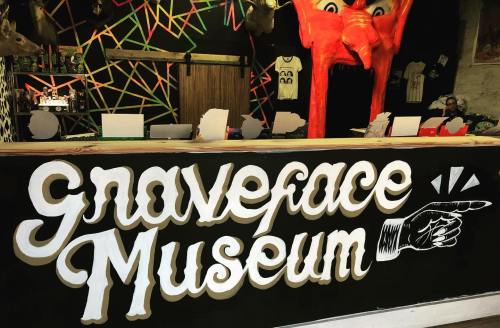 A colorful display featuring the "Graveface Museum" sign with a pointing hand, set against a vibrant backdrop.