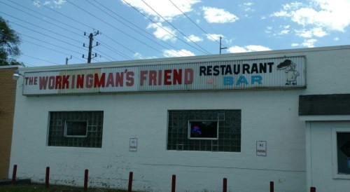 Sign for "The Workingman's Friend" restaurant and bar, featuring a cartoon character and a blue sky backdrop.