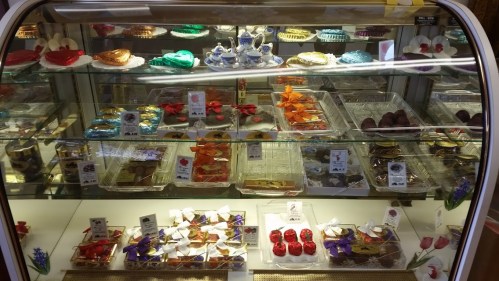 A display case filled with colorful pastries and desserts, including chocolates and decorative sweets.