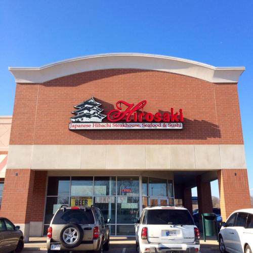 Sign for Hirosaki Japanese Hibachi Steakhouse, Seafood & Sushi on a brick building, with a clear sky above.