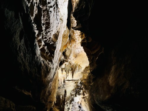 A dark cave with illuminated rock formations and stalactites hanging from the ceiling.