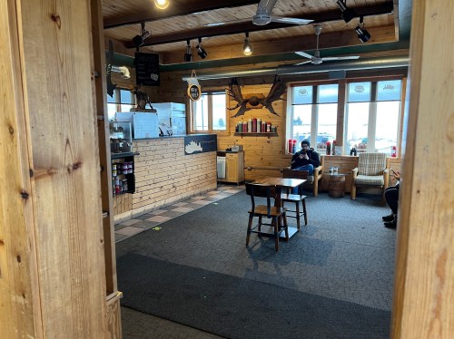 Cozy interior of a rustic café with wooden decor, tables, and patrons seated in a relaxed atmosphere.