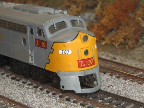 A close-up of a model train engine with a yellow and gray design, featuring the letters "L.N." and the number "787."