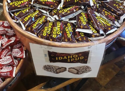A large bowl filled with chocolate-covered Idaho Spud candy bars, with a sign displaying the product name.