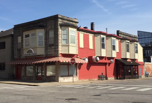 A two-story building with a red and cream exterior, featuring large windows and a striped awning.