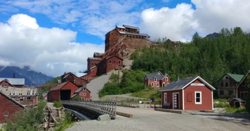 Historic multi-story red wooden mill building built on a steep hillside at Kennecott Mine in Alaska.