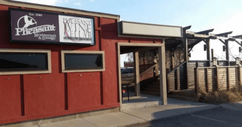 Exterior of Pleasant Restaurant and Wine Cellar, featuring a red building with signage and a wooden patio area.
