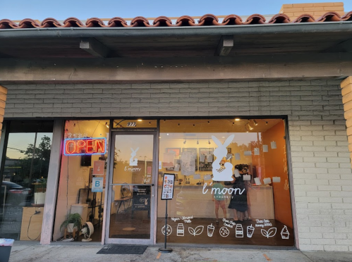 A storefront with a "l'moon" sign and an "OPEN" neon light, featuring a bunny logo and a welcoming atmosphere.