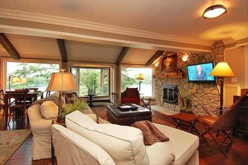 Cozy living room with stone fireplace, large windows, and comfortable seating, overlooking a scenic view.