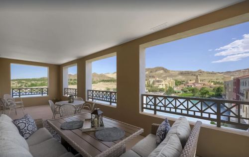 A spacious balcony with comfortable seating, offering scenic views of mountains and a lake.