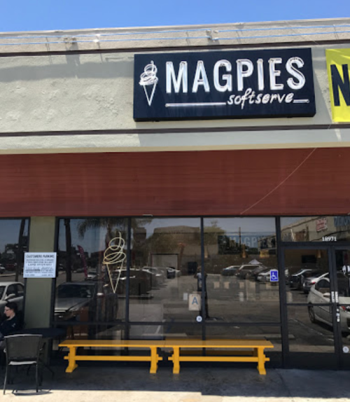 Exterior of Magpies Soft Serve shop with a large sign, featuring a soft serve ice cream cone, and outdoor seating.