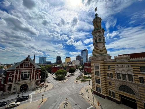 A cityscape featuring a historic tower, modern buildings, and a cloudy sky above a bustling intersection.