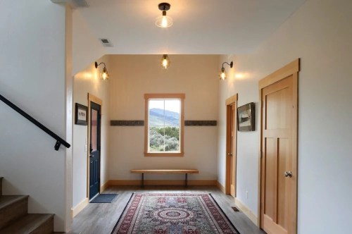 A bright entryway with a patterned rug, wooden bench, and large window showcasing a mountain view.