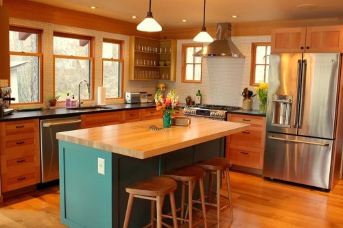 Modern kitchen with wooden cabinets, a large island, stainless steel appliances, and bright natural light.