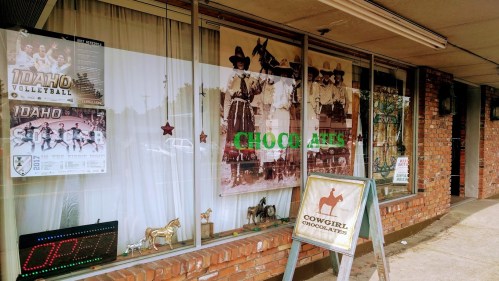 Storefront featuring posters for Idaho volleyball, vintage cowboy images, and a sign for Cowgirl Chocolates.