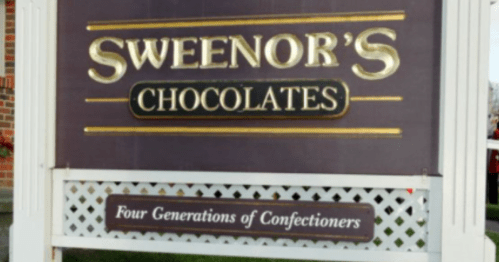 Sign for Sweeney's Chocolates, featuring the text "Four Generations of Confectioners" on a decorative background.