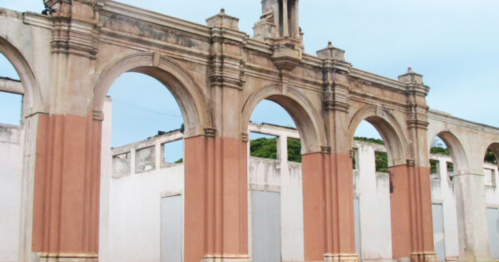 Ruins of a historic building featuring arched structures and faded walls against a clear blue sky.
