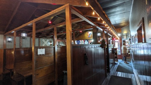 Interior of a rustic restaurant with wooden booths, warm lighting, and a cozy atmosphere.