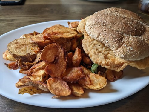 A plate with a crispy chicken sandwich and a generous serving of golden-brown potato chips.