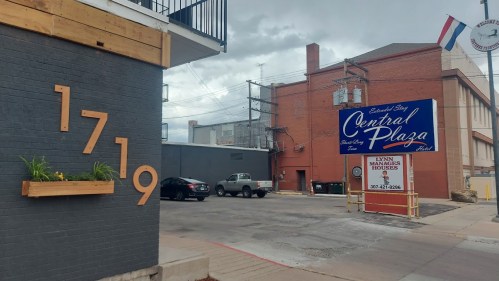 A street view featuring a building with the number 1719 and a sign for Central Plaza, with cloudy skies above.