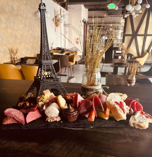 A charcuterie board featuring meats, cheeses, fruits, and a miniature Eiffel Tower centerpiece.
