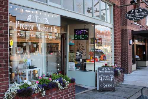 A charming gift shop with a welcoming entrance, featuring colorful flowers and a sign that reads "OPEN."
