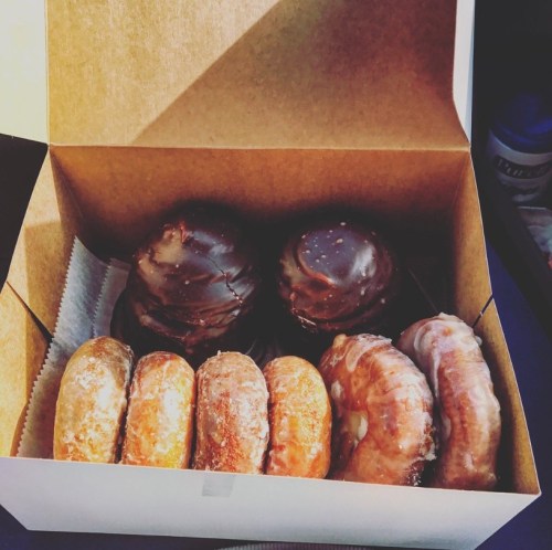 A box of assorted donuts, including chocolate-covered and glazed varieties, arranged neatly inside.