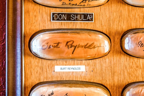 A wooden display featuring signed plaques for Don Shula and Burt Reynolds.