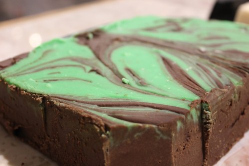 A close-up of a chocolate and mint swirled fudge, featuring vibrant green and brown layers.