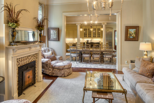 Cozy living room with elegant furniture, a fireplace, and a view into a dining area with a large table.