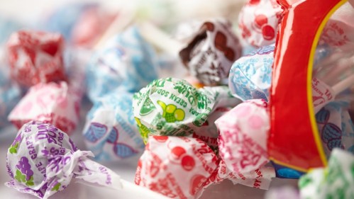 A colorful assortment of lollipops wrapped in various patterned wrappers, scattered on a surface.