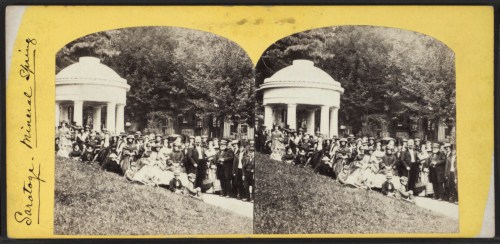 A historic black-and-white photo of a large group of people gathered outdoors near a gazebo in Saratoga Springs.