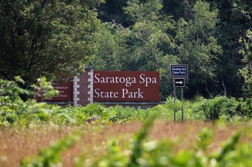Sign for Saratoga Spa State Park, surrounded by greenery, with a directional sign pointing to the park.