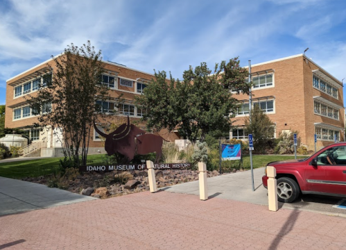 Exterior view of the Idaho Museum of Natural History, featuring a large sign and a red vehicle parked nearby.