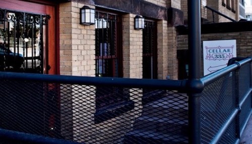 Exterior view of a brick building with a fenced entrance and a sign reading "Cellar 3835."