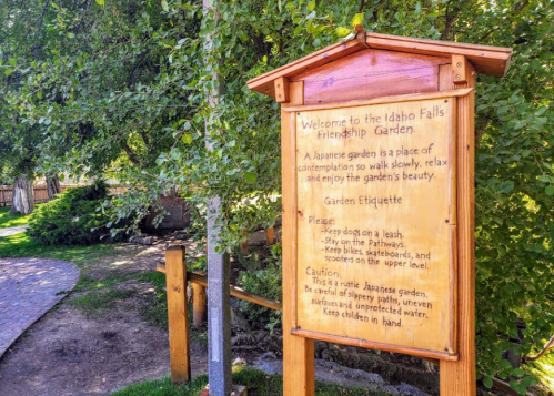Sign at Idaho Falls Friendship Garden, outlining garden etiquette and safety guidelines in a serene, green setting.