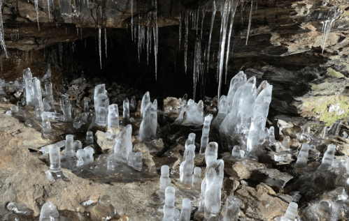 A cave interior featuring various ice formations and icicles on rocky surfaces.