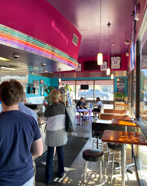 A colorful diner interior with patrons seated and in line, featuring bright walls and a vibrant atmosphere.