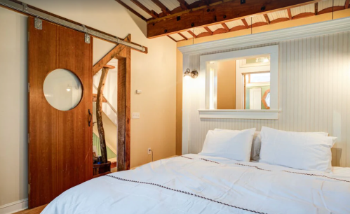 Cozy bedroom featuring a large bed, wooden accents, and a sliding barn door. Natural light from a window.