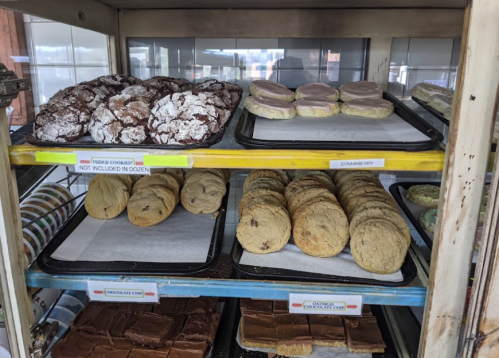 A display case filled with various cookies, including chocolate crinkle, iced cookies, and chocolate chip.