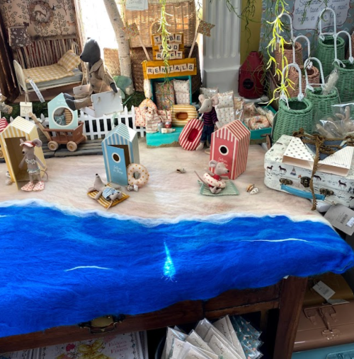 A colorful display of decorative items, including birdhouses and toys, set on a blue felt ocean backdrop.